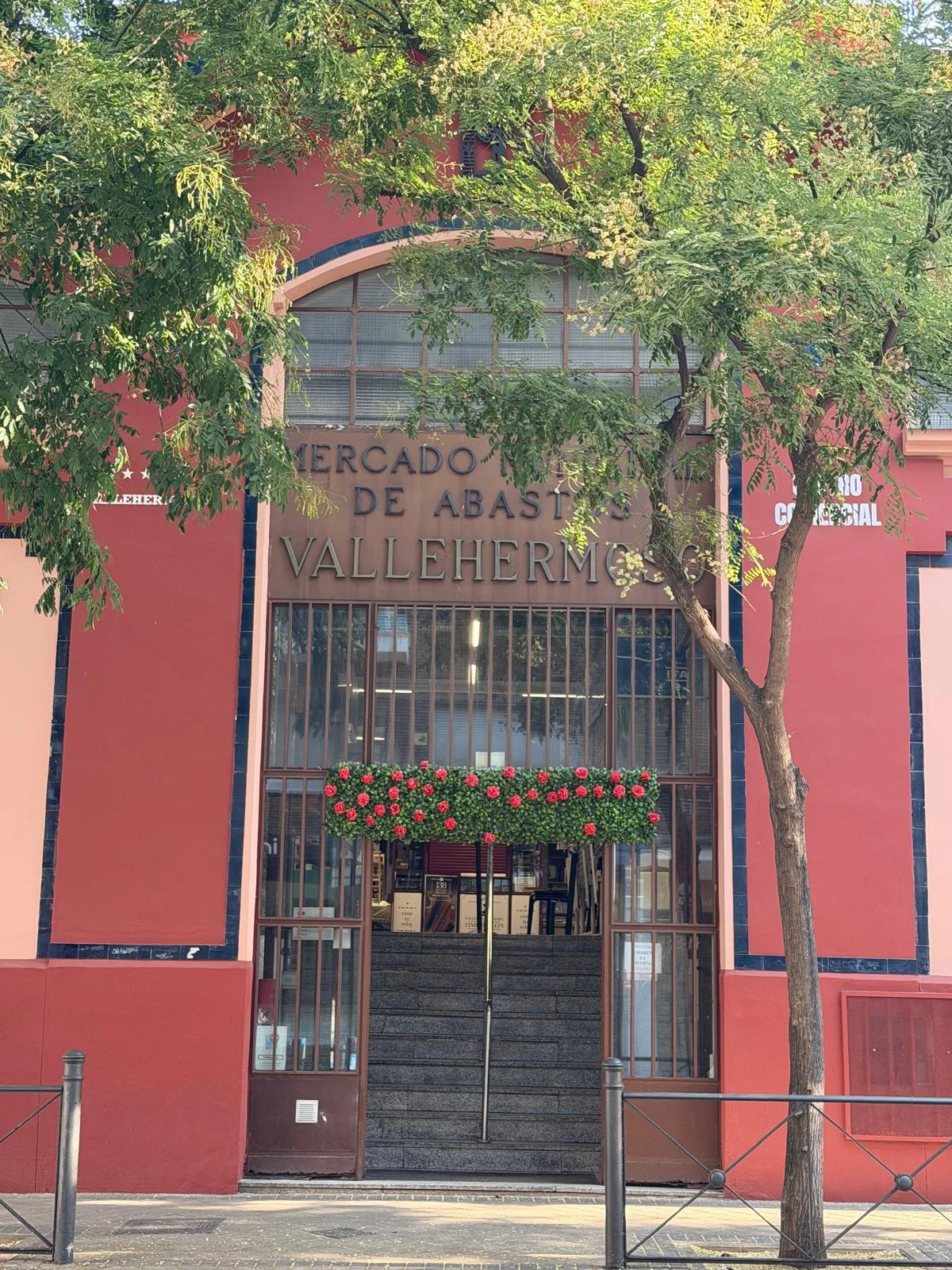 Calle residencial de Chamberí por la mañana, balcones con rejas de hierro, toldos, movimiento discreto de vecinos.